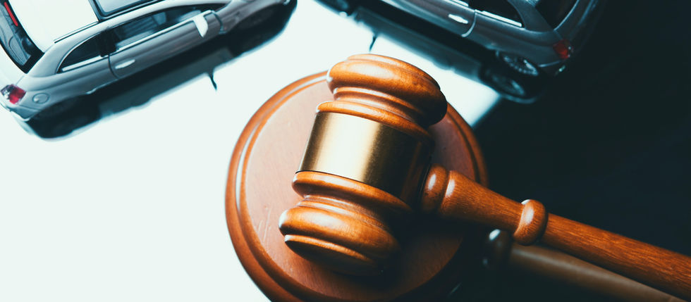 Gavel on a wooden block with two toy cars, symbolizing legal issues. The scene is set on a reflective surface, creating a dramatic mood.