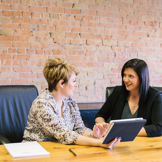 Two women having a business meeting at a wooden table with a tablet