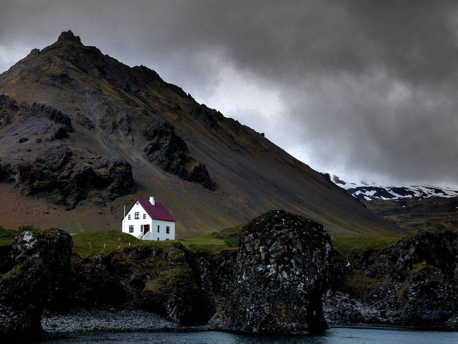 Small white church in Vík í Mýrdal beneath dramatic mountains and black sand landscapes in South Iceland.