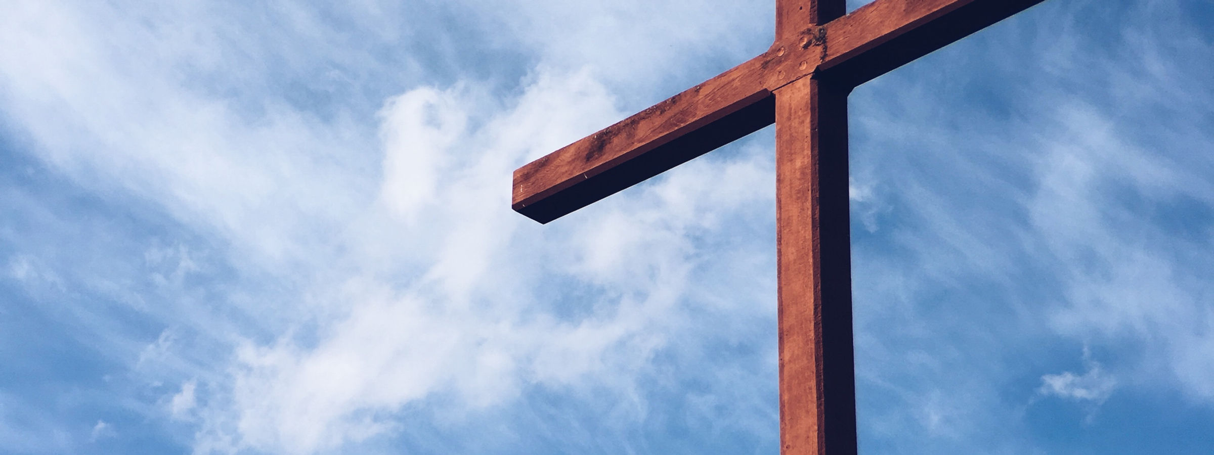 Image of a cross in front of the sky by Aaron Burden