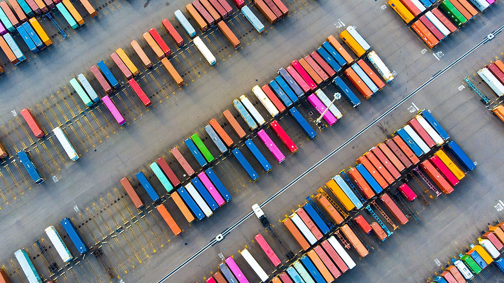 Wide-angle view of stacked shipping containers near a working rail yard.
