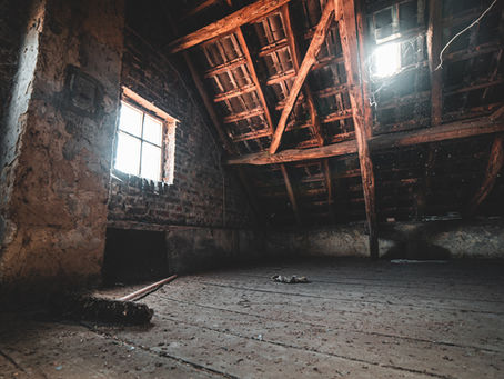 Sunlight streams through a dusty attic's wooden beams and window, illuminating cobwebs and a broom on the wooden floor. Mood is rustic.