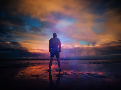 A man standing on beach at sunset.