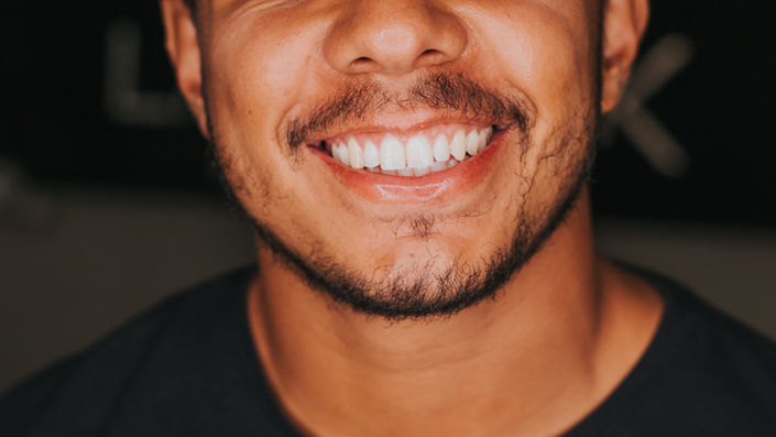 A man with a natural smile and clean teeth standing in front of camera