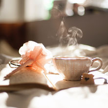 In the soft morning light, a steaming cup of tea accompanies a journal and a delicate feather pen, inviting moments of reflection and creativity.