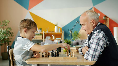 un enfant et un homme agé jouent ensemble aux échecs