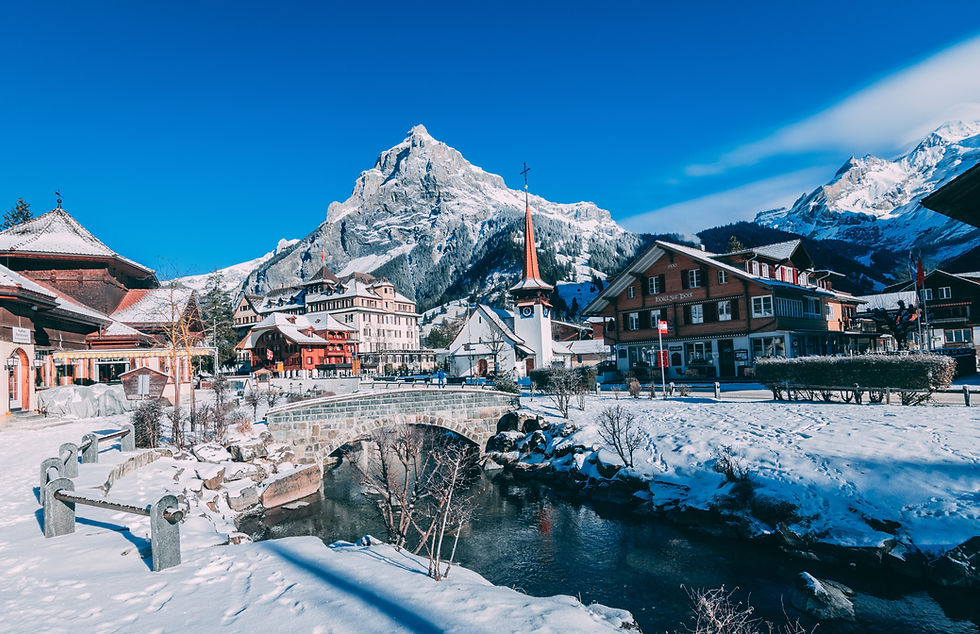 Verschneites Bergdorf in den Schweizer Alpen unter strahlend blauem Himmel – traditionelle Holzhäuser, schneebedeckte Dächer und majestätische Berggipfel im Hintergrund.