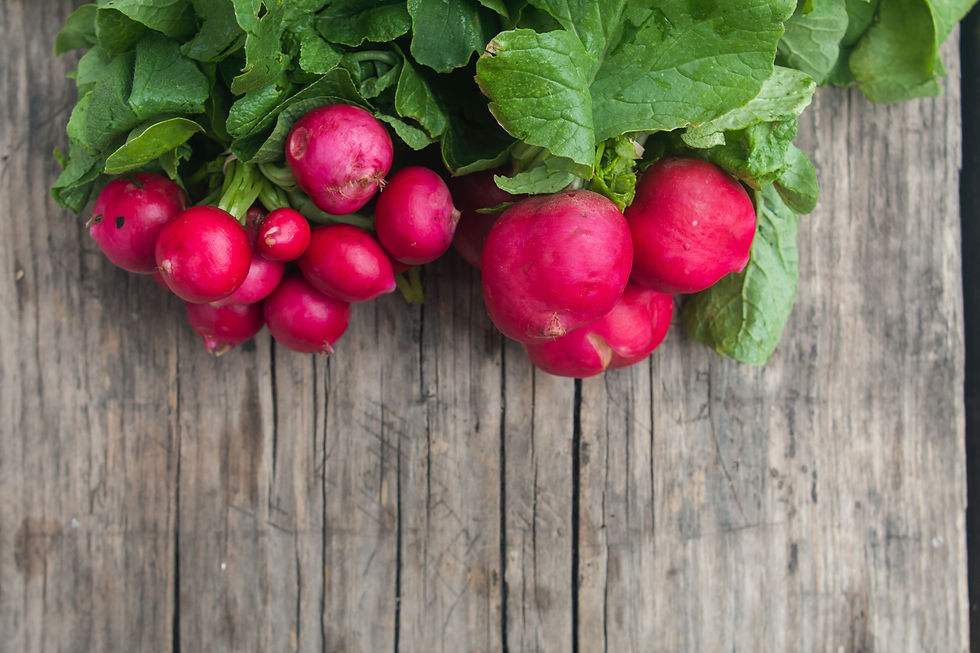 Bunch of vibrant red radishes with green leaves on a rustic wooden table, creating a fresh and natural display.