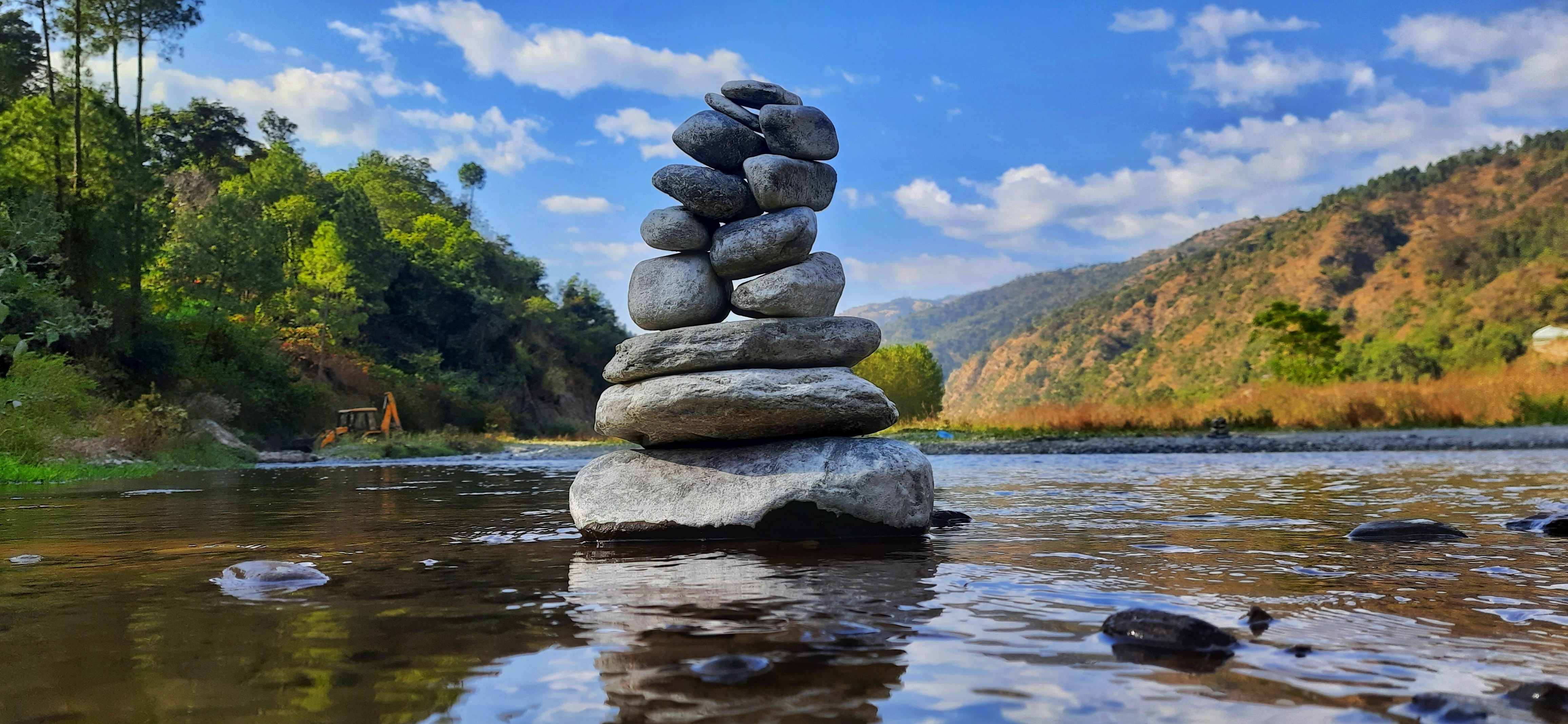 Balanced stones beside water — photograph by Tushar Rathour