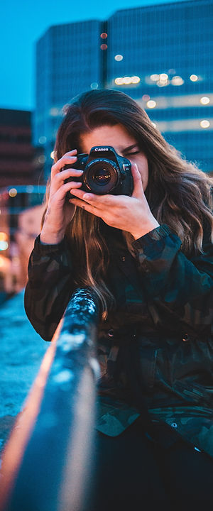 Woman photographs cityscape at dusk