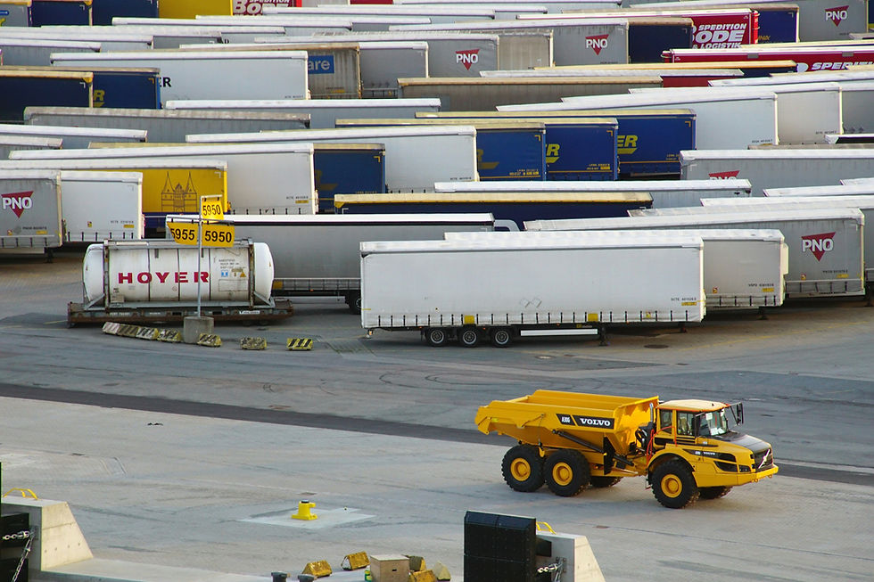 Yellow Volvo truck on a paved lot with multiple parked trailers in the background. Some trailers have logos and numbers visible.
