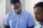 Young African American doctor and nurse in hospital wearing blue scrubs.
