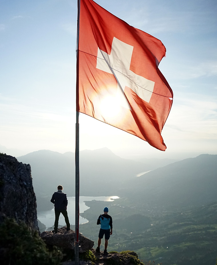 Swiss flag on mountain with two people