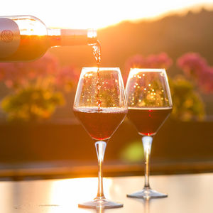 Red wine being poured into a glass in front of a sunset