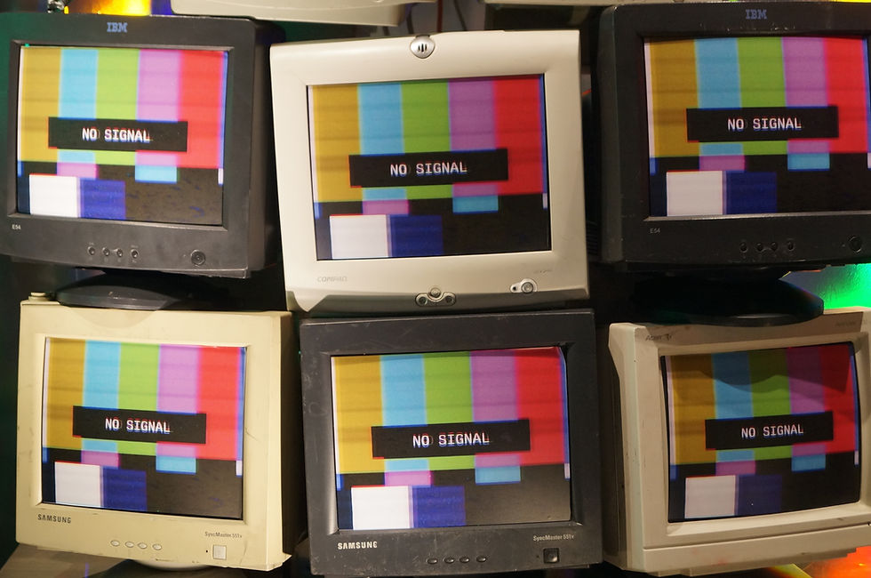 Six vintage monitors display "NO SIGNAL" over color bars, stacked and arranged haphazardly, creating a retro, chaotic atmosphere.