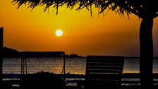 Silhouette of chair watching the sunset over the still ocean