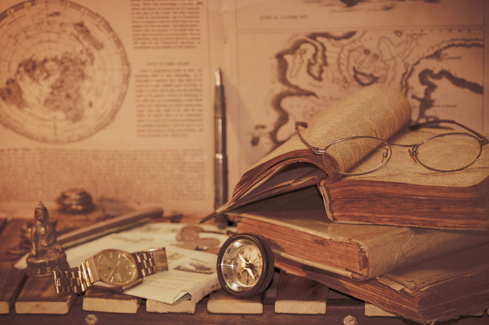 Vintage-Schreibtischszene mit alten Büchern, einer Taschenuhr, einer Brille und antiken Karten. Die Gegenstände vermitteln eine historische Atmosphäre und erinnern an Entdeckungen und Wissen vergangener Zeiten.