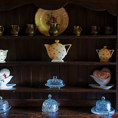 Teapots displayed on a dark wooden hutch
