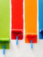 4 Paint rollers with different colors lime green, red, orange and blue on a white background