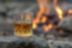 Whisky glass resting on rock, in front of fire