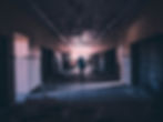 Person walking toward the light in a bleak hallway