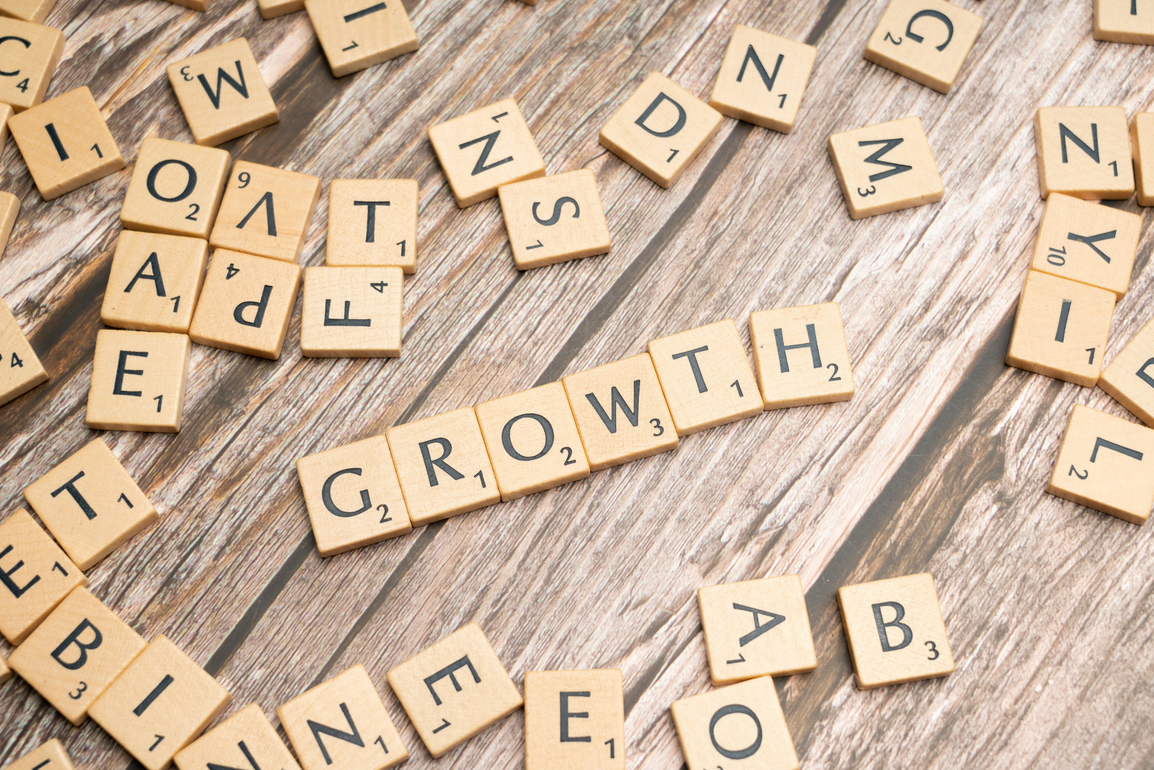 Wooden letter tiles spelling out the word "GROWTH" on a rustic wooden background.