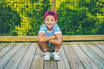 Boy outside with pink hat, smiling