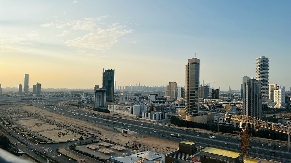 City skyline at dusk with tall buildings and a construction crane. The sky is partly cloudy with soft, warm light, suggesting a calm mood.