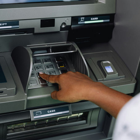 A woman's hand pressing button on an ATM keypad, with text "RECEIPT" and "CASH" visible. Gray machine, modern and clean setting.