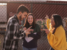 Three teenagers outside talking about their schedule.