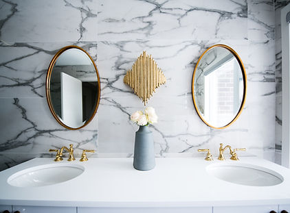 Luxury bathroom with marble walls and double sinks with gold accents