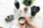 Desk with camera and the hand of a person holding coffee