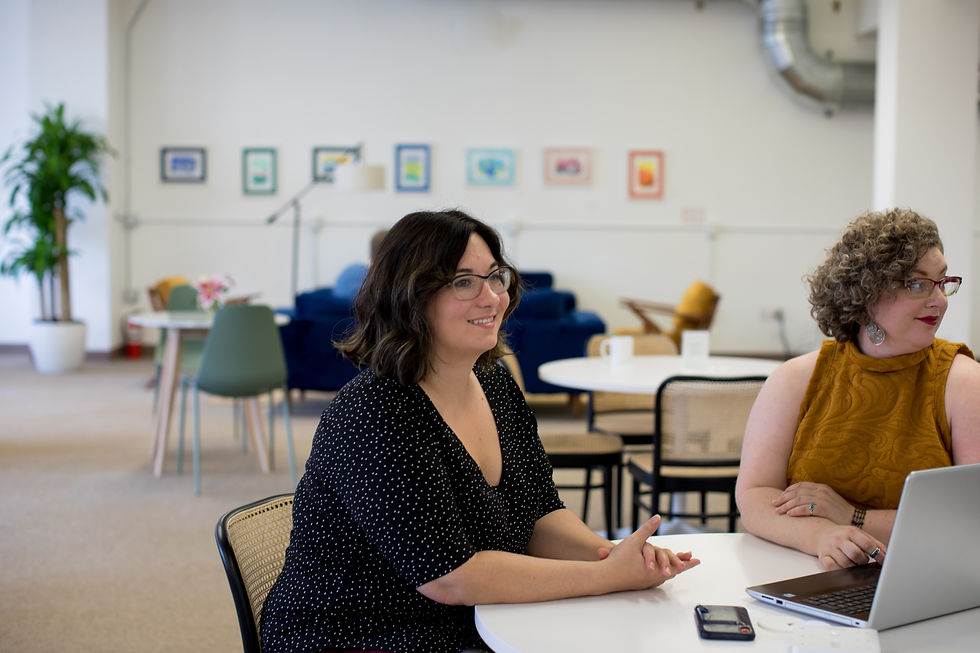 Two women sitting together at a desk in a bright, modern office
