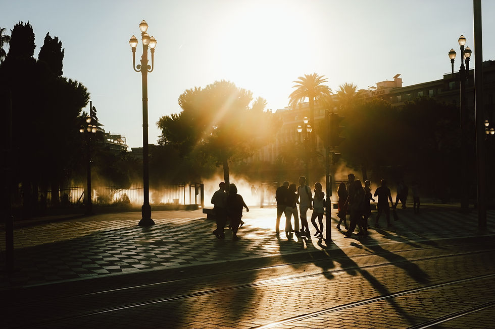 People walking along a treelined street at sunset.