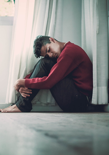 young man sitting on the floor hugging knees, holistic therapy, st. petersburg counselor