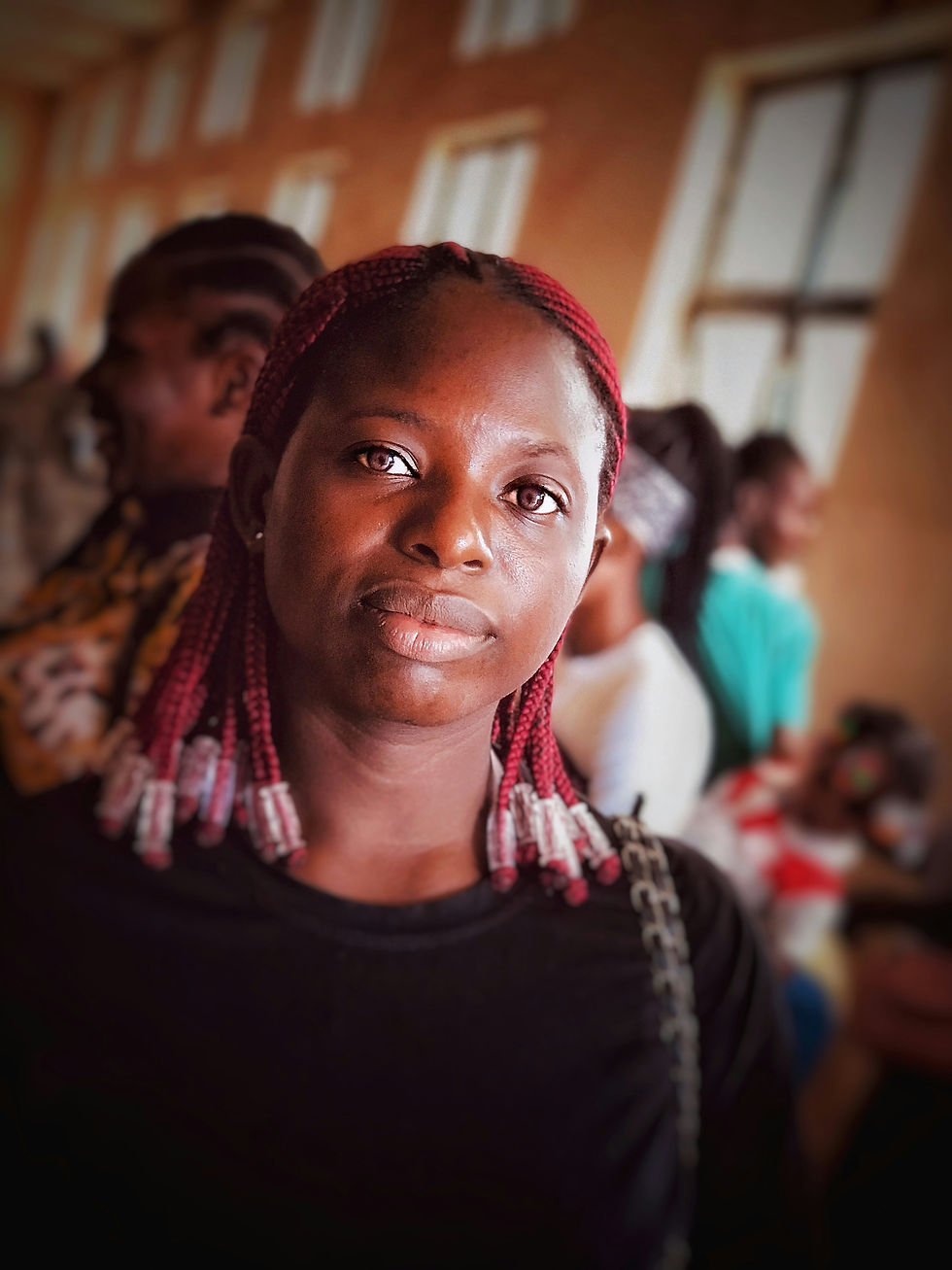 portrait d'une jeune femme noire avec tresses rouges dans les cheveux dans une école