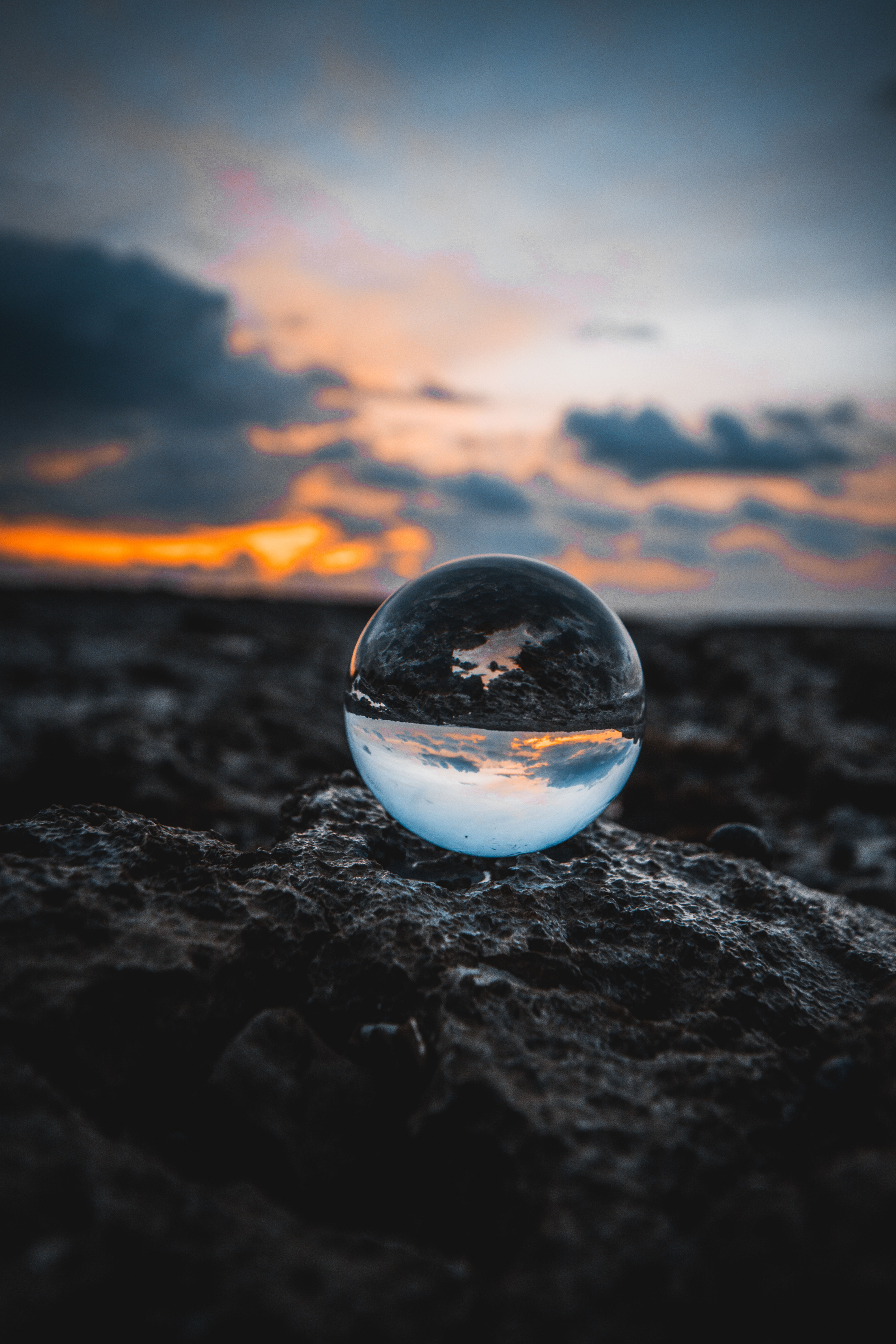 A natural scene with sunset and rocks, and a glass globe refracting the scene (upside down)