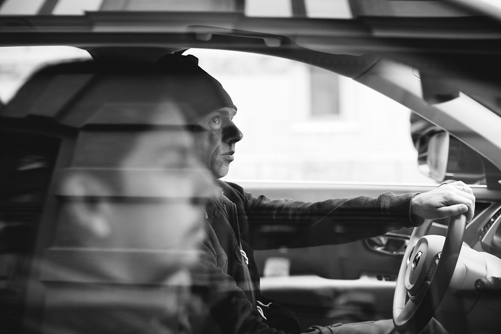 Black and white photo of two people driving in the front seat of a car.
