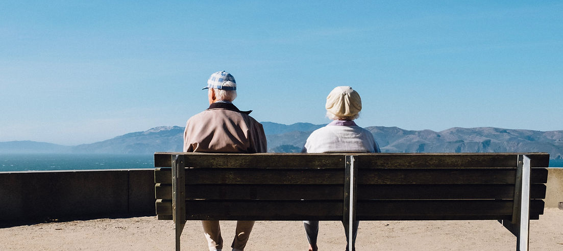 Senior couple sitting on bench looking at the mountains