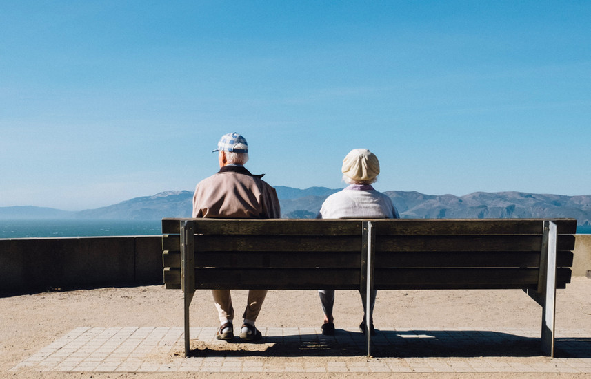 Older couple sitting on a bench outside.