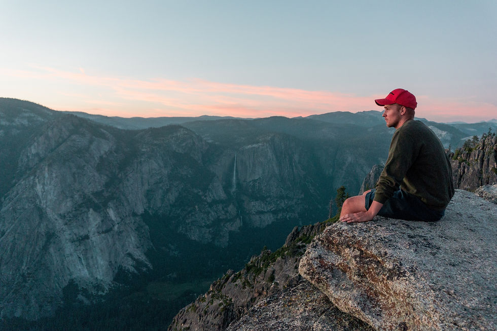 A person sitting on a rock looking at a valley