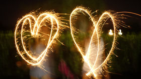 Two sparkler hearts glowing against dark background - choosing words that create light and connection