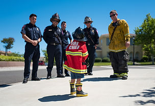 Image of a child in fire chief outfit in front of first responders