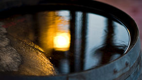 Barrel of moonshine liquor with moonlight reflected in water collected on top of barrel