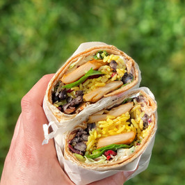 hand holding two sides of a wrap with veggies and sauce