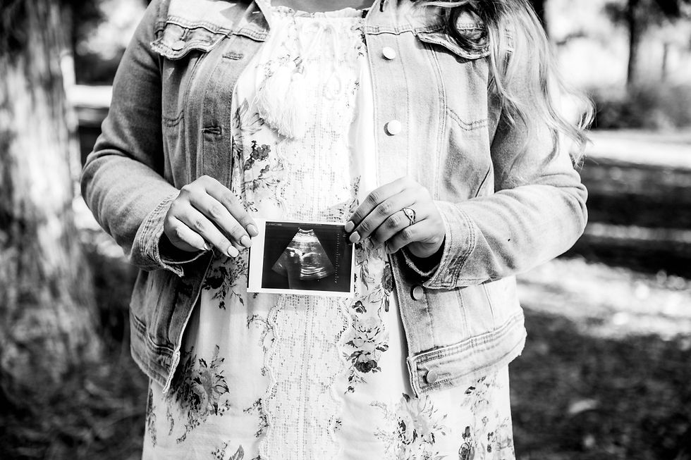 Pregnant woman holding her baby's ultrasound while waiting for pregnancy results.