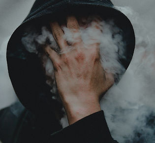 man with hood up covers face which is covered by smoke