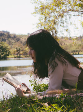 Jonge vrouw leest een boek aan een meer