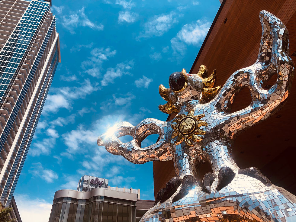Mosaic sculpture in front of city skyscrapers