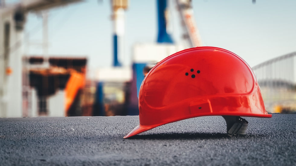 An engineer helmet on the ground with a blurry port in the background.